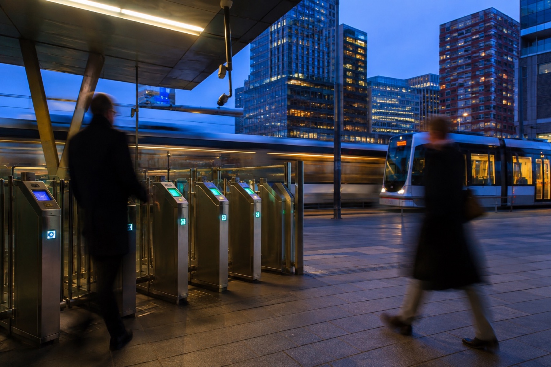 Reizigers bij de poortjes van een metrostation in de avond